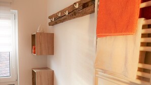 Ein Badezimmer mit Holzregal, Handtuchhalter und einer kleinen Bank.