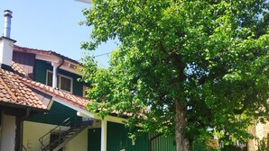 Ein grünes Gebäude mit einem Ziegeldach, einer Treppe und einem Baum im Hof.