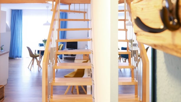 Un interno moderno con una scala in legno che conduce a una sala da pranzo.