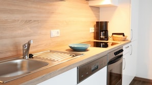 Una cucina moderna con lavello in acciaio inox, macchina da caffè e lavastoviglie.