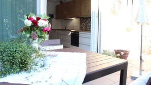 A dining area with a table set for two, a vase of flowers, and a view of the kitchen in the background. - House Apple Blossom - No 3 (Langenargen)