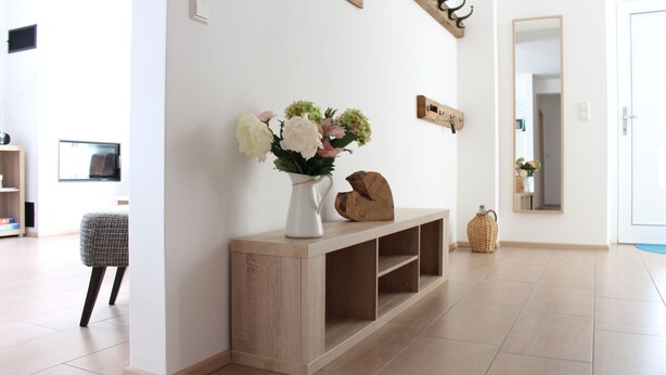 A modern living room with a wooden console table, a vase of flowers, and a mirror on the wall. - House Apple Blossom - No 3 (Langenargen)