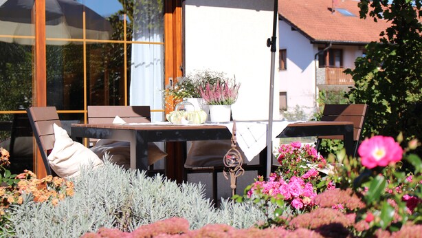An outdoor seating area with a table and chairs, surrounded by various plants and flowers. - House Apple Blossom - No 4 (Langenargen)