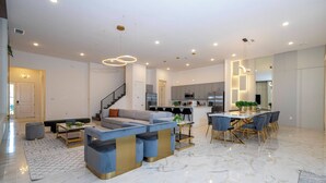 Ein geräumiger Wohnbereich mit einer modernen Couch, einem Esstisch mit Stühlen und einer Küche im Hintergrund.