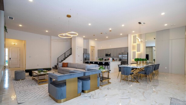 A spacious living area with a modern sofa, a dining table with chairs, and a kitchen in the background. - 15BR Ultimate Disney Group Getaway (5812PG) (Orlando)