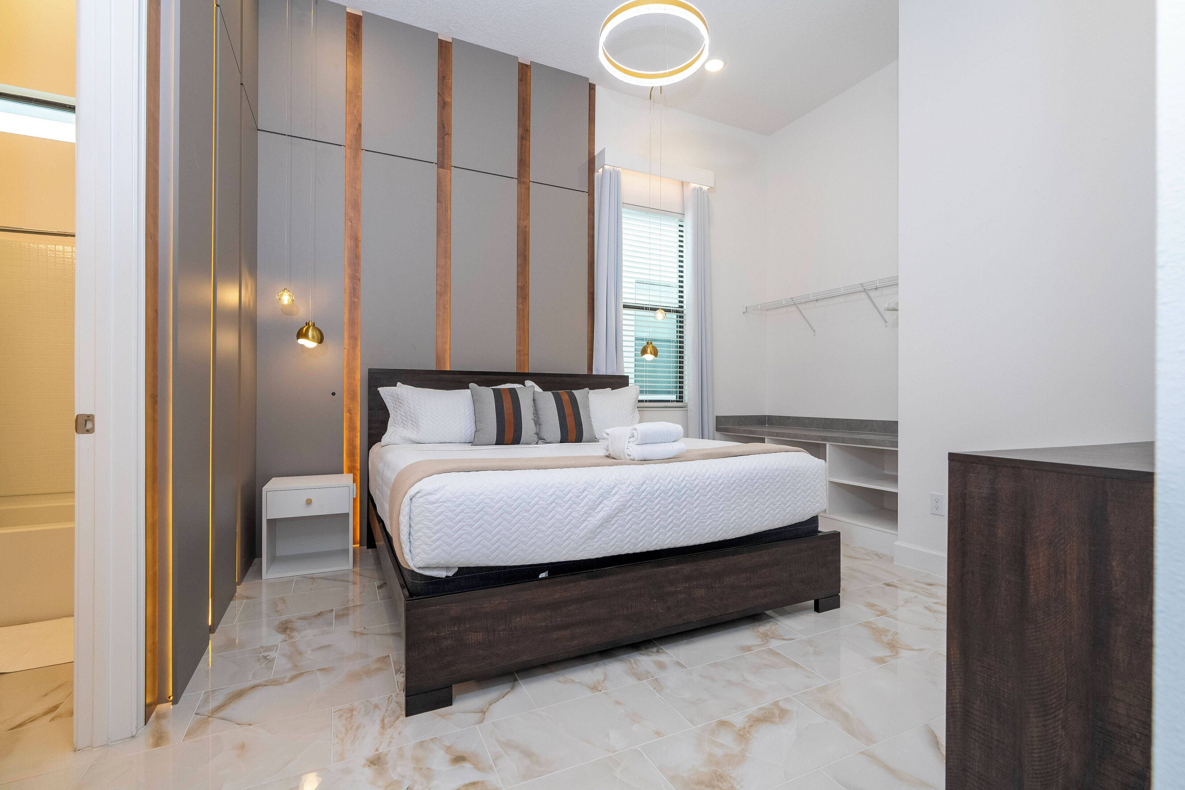 A modern bedroom with a large bed, a bedside table, a nightstand, and a built-in bench.