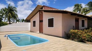 Un edificio con piscina, palme e cielo sereno.