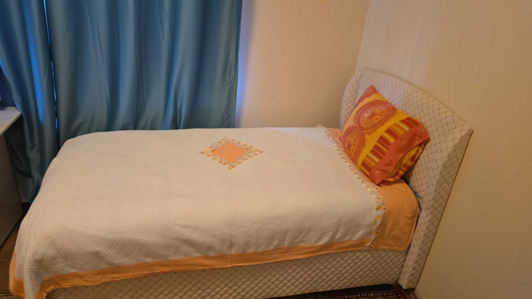 Ein Bett mit gesteppter Decke und einem Zierkissen.