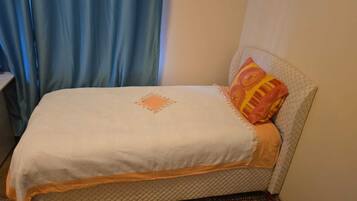 Ein Bett mit gesteppter Decke und einem Zierkissen.