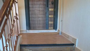 Una escalera de madera con barandilla metálica que lleva a una puerta con un panel decorativo.
