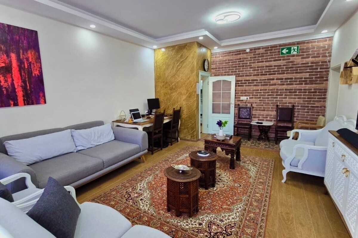 A modern living room with a grey sofa, a white armchair, a coffee table, and a patterned rug.