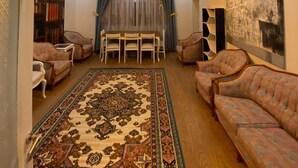 A living room with a patterned rug, sofas, a dining table with chairs, and a ceiling light fixture. - Hibe Dede Hotel Cappadocia (Ürgüp)