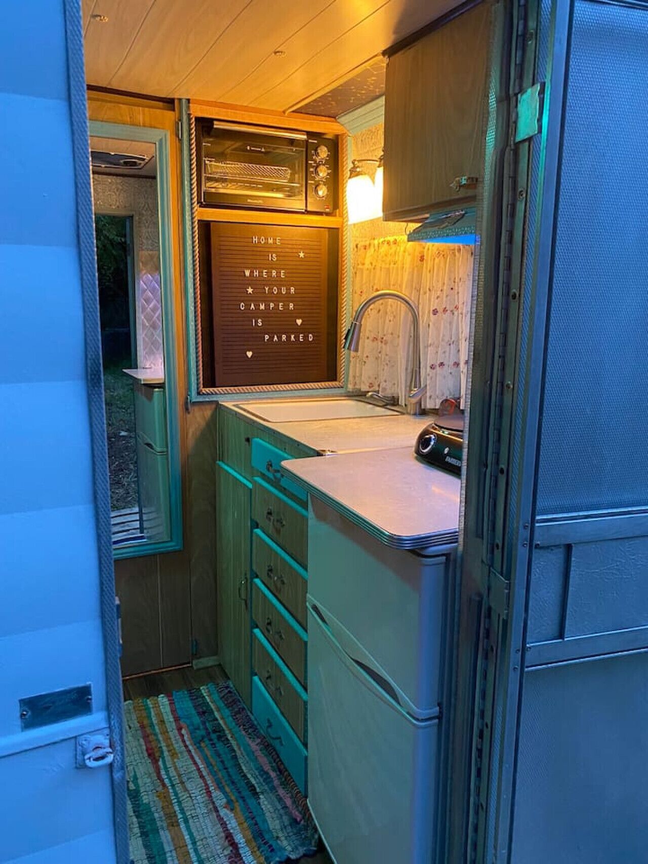 A compact kitchenette with a built-in oven, a sink, and a message board.