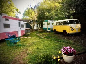 A backyard with two vintage campers parked, a small lawn, and a potted plant with flowers. - 1951 Spartan Aircraft Cottage w/AC - Durham, NC (Durham)