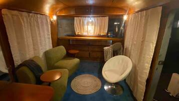 A compact living space with a sofa, armchair, small round table, and a bar area with a window.