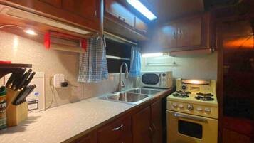 A compact kitchen with a microwave, stove, and sink.