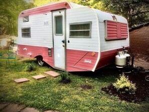 A vintage camper with a door, windows, and a red and white exterior.
