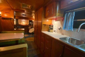 A compact kitchen with wooden cabinets, a sink, and a dining area with a table and chairs.