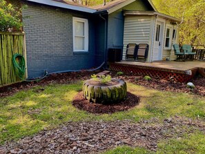 A backyard with a tire planter, a wooden fence, and a house with a garage. - 1951 Spartan Aircraft Cottage w/AC - Durham, NC (Durham)