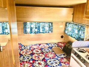 A compact RV interior with a quilted floor, a stove, and curtains with a nautical theme. - 1966 Shasta Cottage w/AC - Durham, NC (Durham)