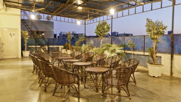 An outdoor seating area with wicker furniture and potted plants. - Hotel Holy City (Amritsar)