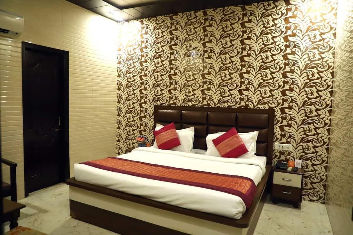 Une chambre d’hôtel avec un grand lit, une table de chevet et un papier peint à motifs.