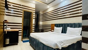A modern bedroom with a large bed, a ceiling fan, and a TV. - Hotel Holy City (Amritsar)