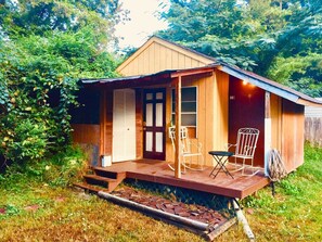 Eine kleine Holzhütte mit Veranda, zwei Schaukelstühlen und einer Tür mit Fenster.