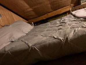 Ein Bett mit einer gesteppten Matratze und einem Kopfkissen.