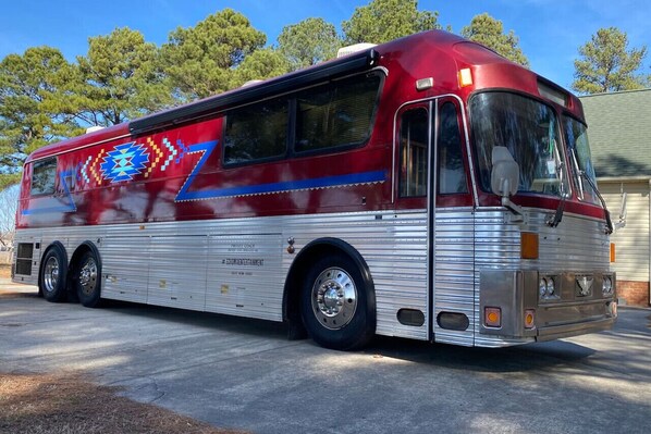 A red and silver bus with a decorative design on the side, parked on a concrete surface.