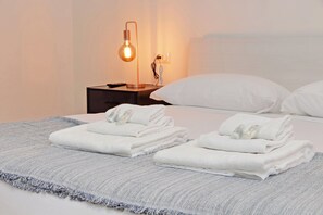 A neatly made bed with white pillows and folded towels, a bedside lamp, and a power outlet on a nightstand. - 4BNB - Baldo degli Ubaldi Big Apartment (Rome)