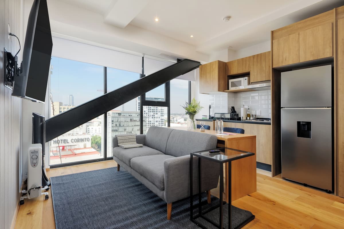 A modern kitchen with wooden cabinets, a stainless steel refrigerator, and a view of the city.