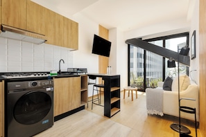 A modern kitchen with a washing machine, a TV, and a balcony with a view.