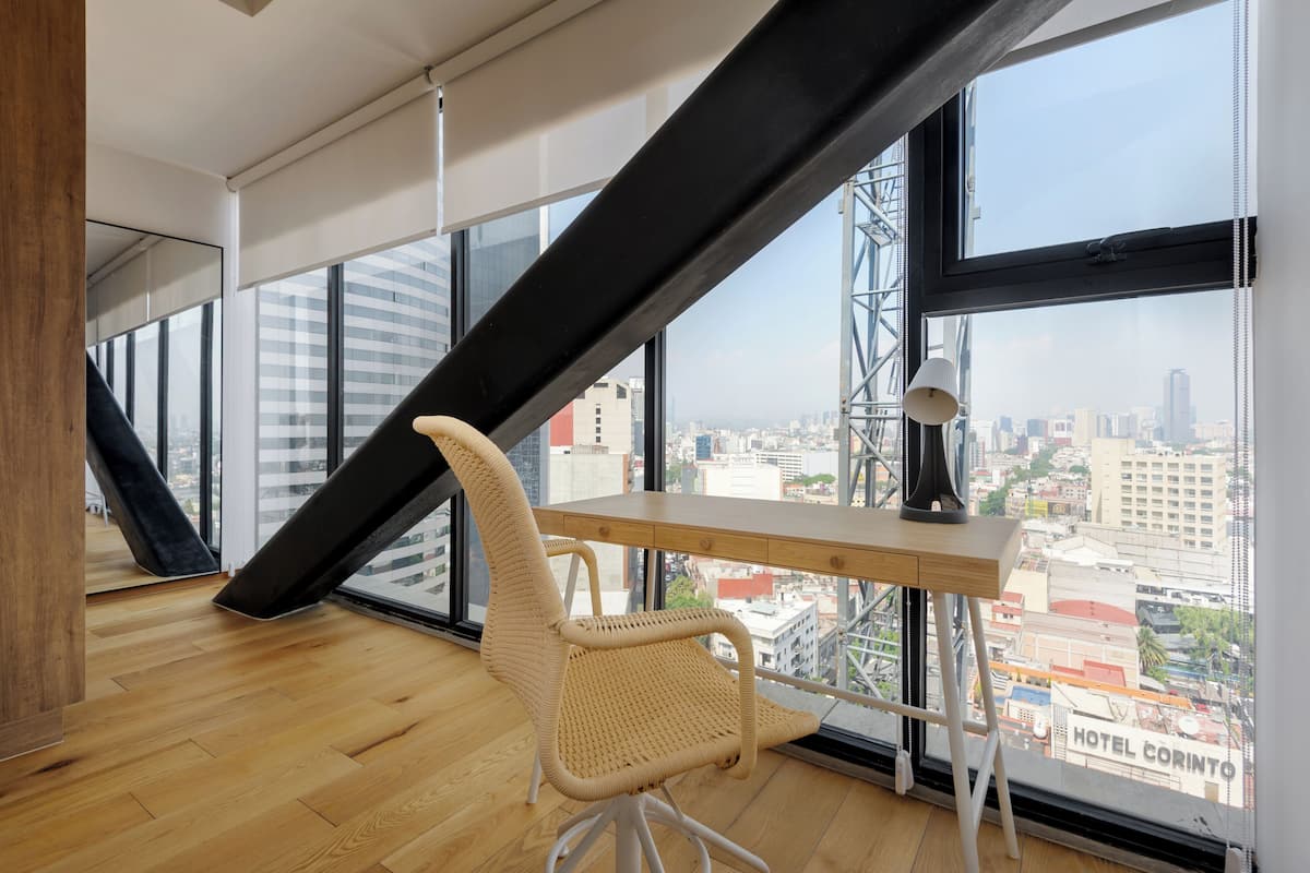 A modern office space with a large window, a desk, a chair, and a view of the cityscape.