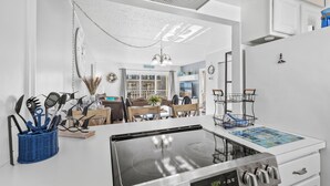 Eine moderne Küche mit Einbauherd, eine Essecke mit Tisch und Stühlen sowie ein Wohnzimmer mit Sofa und Fernseher.
