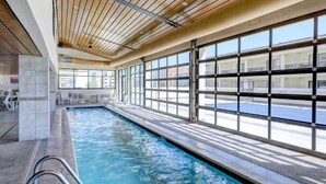An indoor swimming pool with clear windows and a wooden ceiling.