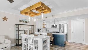 A modern kitchen with white cabinetry, a wooden ceiling, and pendant lighting.