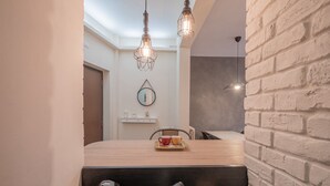 A modern kitchen with a wooden table, two kettles, and a brick wall.