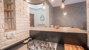 A modern kitchen with a brick wall, a wooden countertop, and a gas stove.