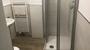 A small bathroom with a shower, sink, and towel rack.