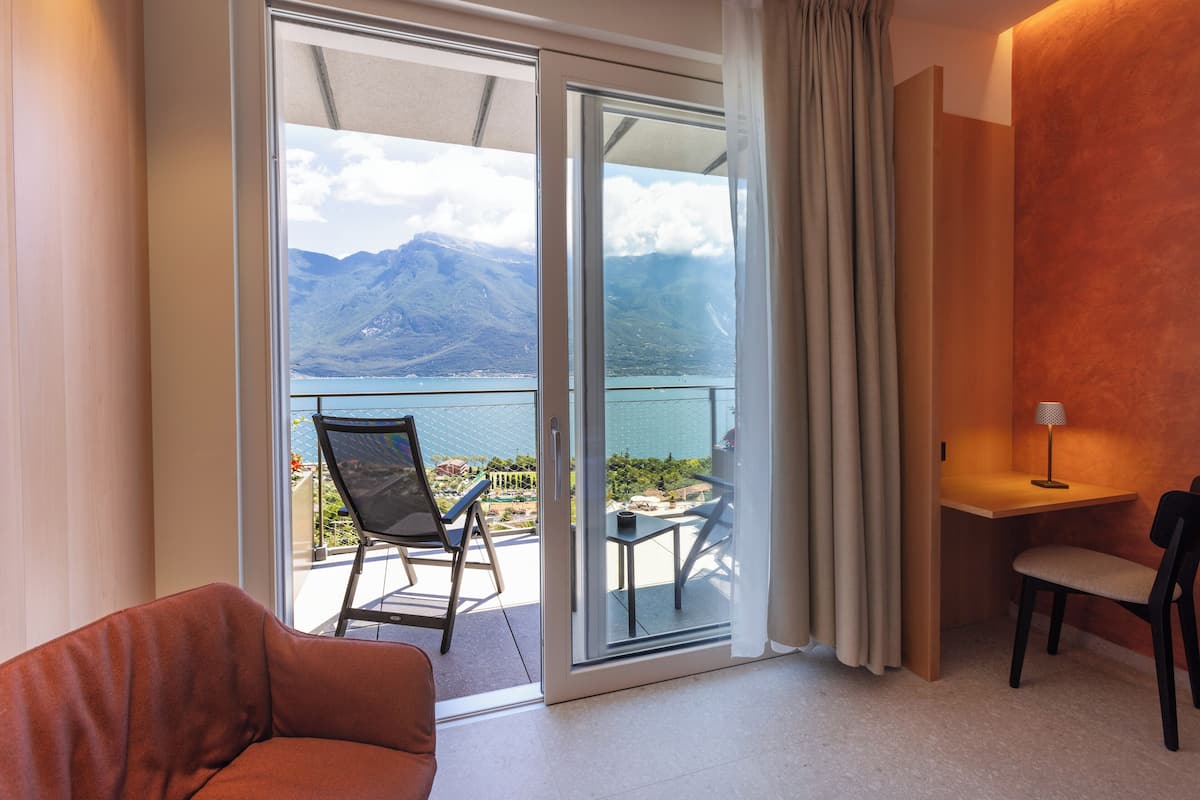 A room with a sliding glass door leading to a balcony with a mountain view.