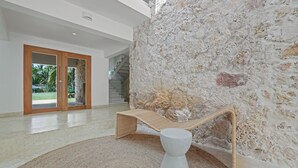 Ein modernes Interieur mit einer Steinwand, einem Korbsessel und einem weißen Podest.