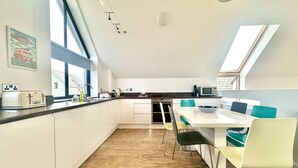 Una cocina moderna con comedor, ventanas amplias y tragaluces.