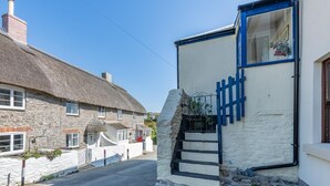 A narrow street with a stone house and a white building with a blue gate. - 3 Bed in East Prawle (oc-t30117) (East Prawle)