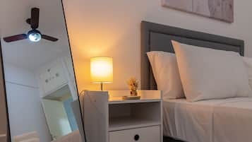 A bedroom with a bed, bedside table, lamp, and a large mirror.