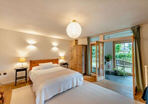 Relax in this serene bedroom with a large bed, bedside tables, and a sliding door leading to an outdoor area with a view.