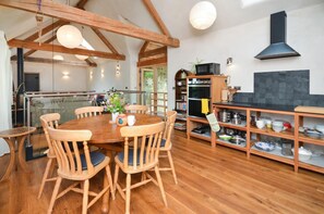 Une cuisine spacieuse avec un plancher en bois, une table de salle à manger ronde entourée de chaises et un four encastré.
