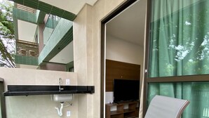A balcony with a sink, a chair, and a TV in the background. - Flat a 120 metros das Piscinas Naturais (Ipojuca)