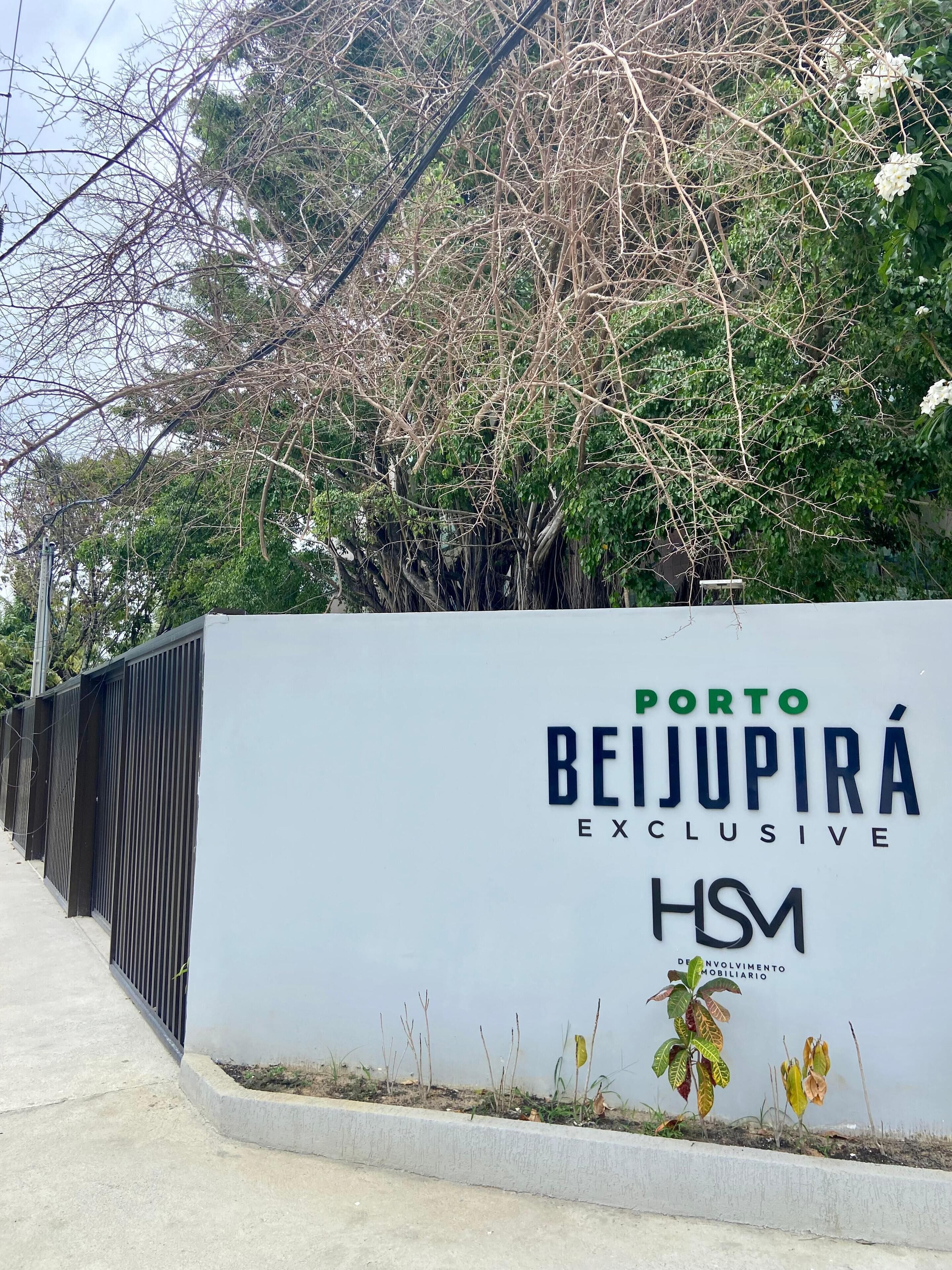 Une enseigne pour le Porto Beijupira Exclusive HSM, avec une clôture en métal et de la verdure en arrière-plan.