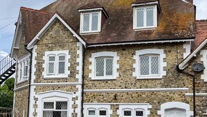 Un edificio de piedra de dos pisos con numerosas ventanas y una chimenea.